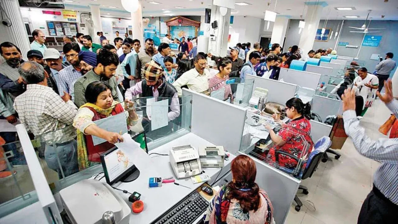 A crowded bank branch in India, people pressing at the counters